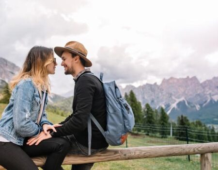 Charming girl in vintage denim jacket relaxing with her boyfriend spending time outdoor with mountains